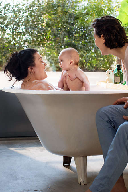 Ein Baby in der Badewanne mit zwei Frauen