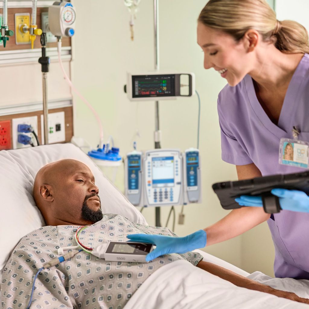 Clinician interacting with telemetry data with iPad in hand at the bedside on the Telemetry Monitor 5500