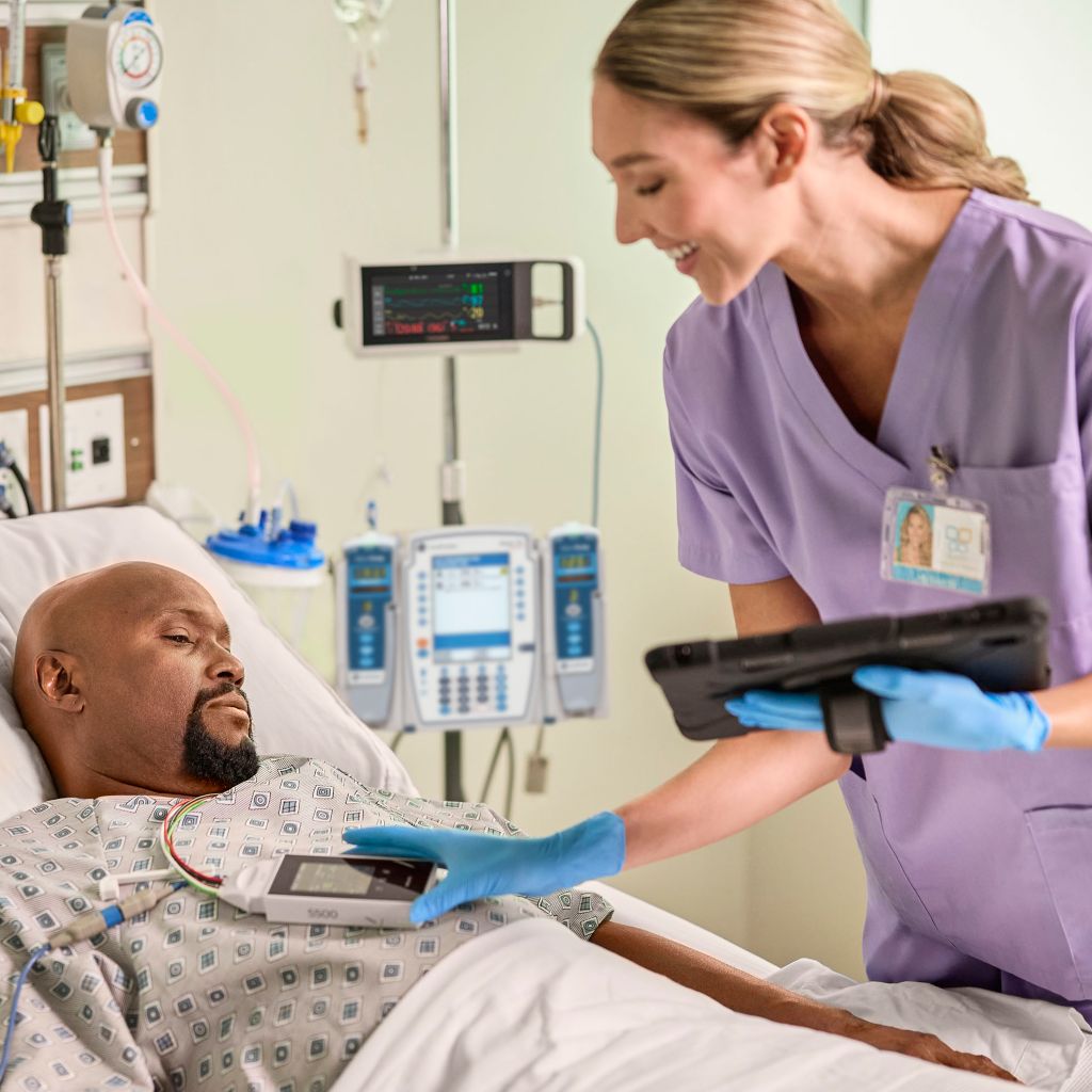 Clinician interacting with telemetry data with iPad in hand at the bedside on the Telemetry Monitor 5500