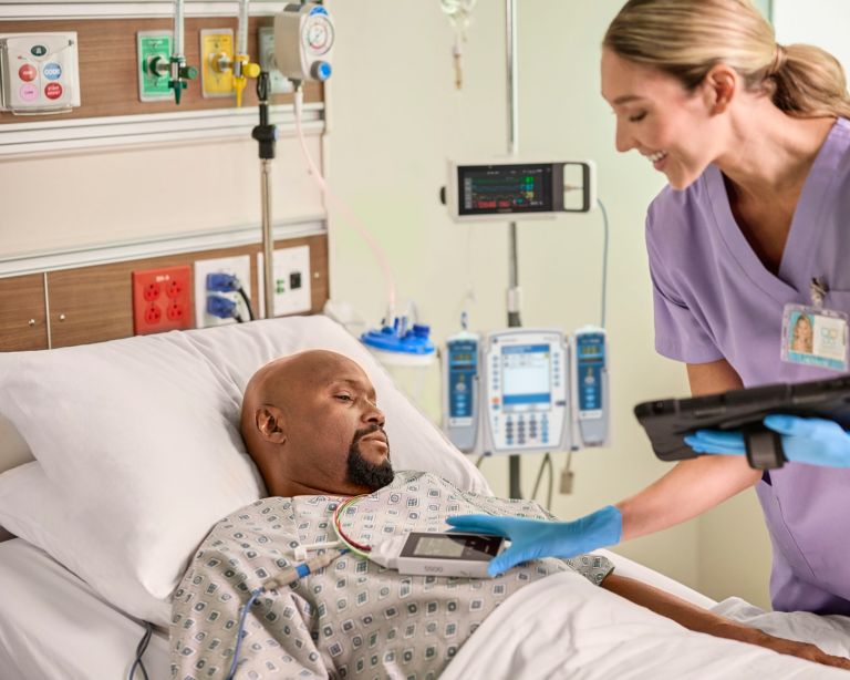 Clinician interacting with telemetry data with iPad in hand at the bedside on the Telemetry Monitor 5500
