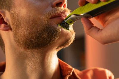 Primeiro plano de um homem a barbear a sua barba densa com a OneBlade da Philips