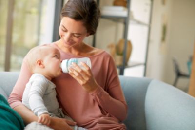 Mother feeding baby with Philips Avent AirFree baby bottle