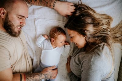 Parents lying with newborn baby on bed bonding as a family