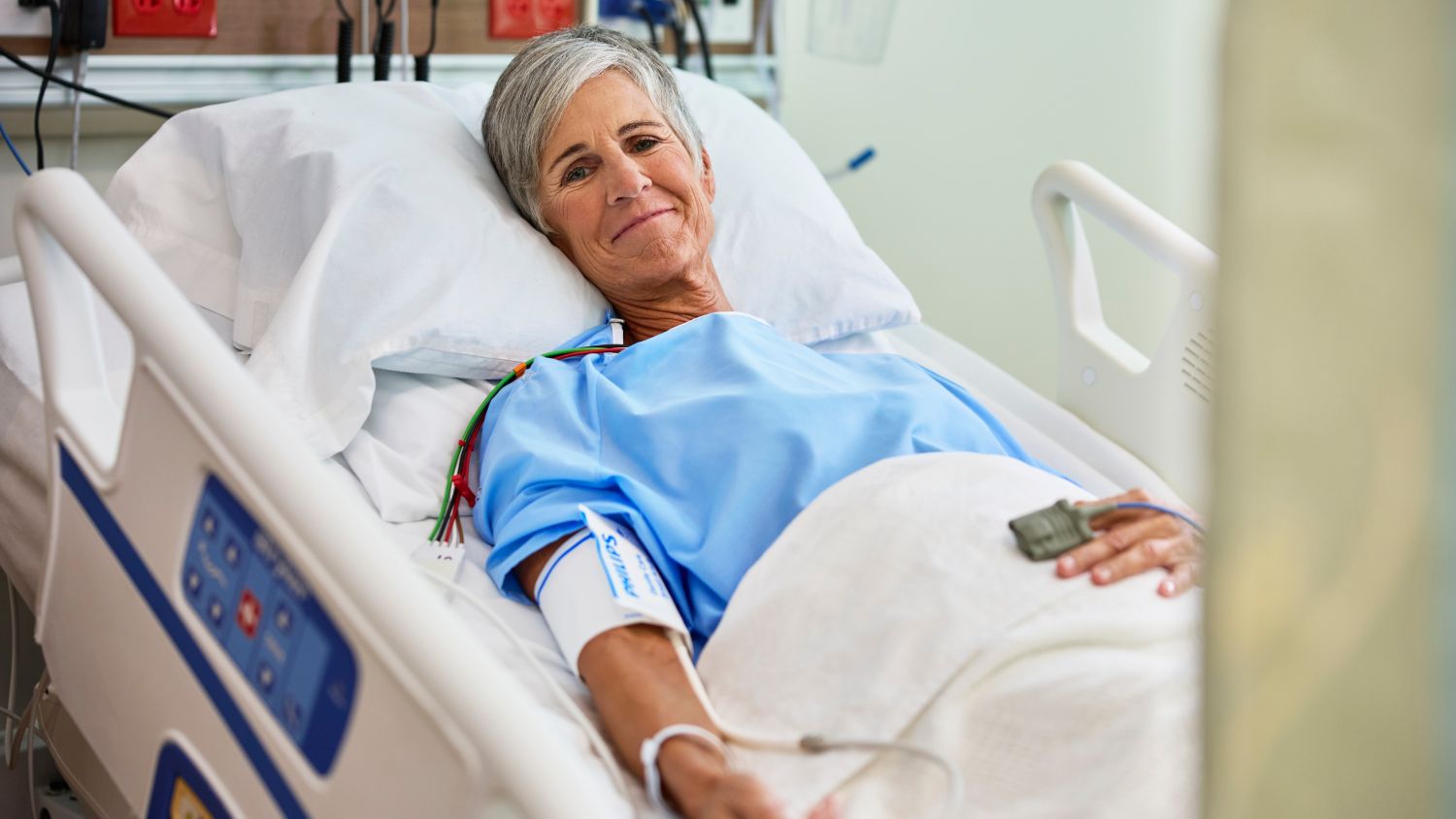 Woman in hospital bed with SpO2 sensor and NBP cuff