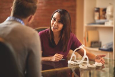 Clinician showing a CPAP mask with updated headgear and nasal cushion