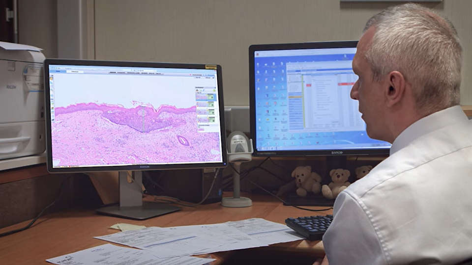 Pathologist evaluating a digital pathology case on a desktop monitor
