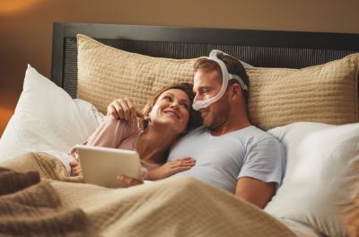 Patient awake in bed with partner, wearing a mask