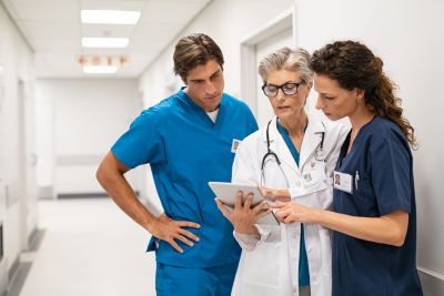 Healthcare team reviewing patient data on tablet in hospital corridor