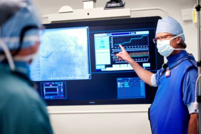 Interventional cardiologist pointing to real-time iFR and angiography display during procedure