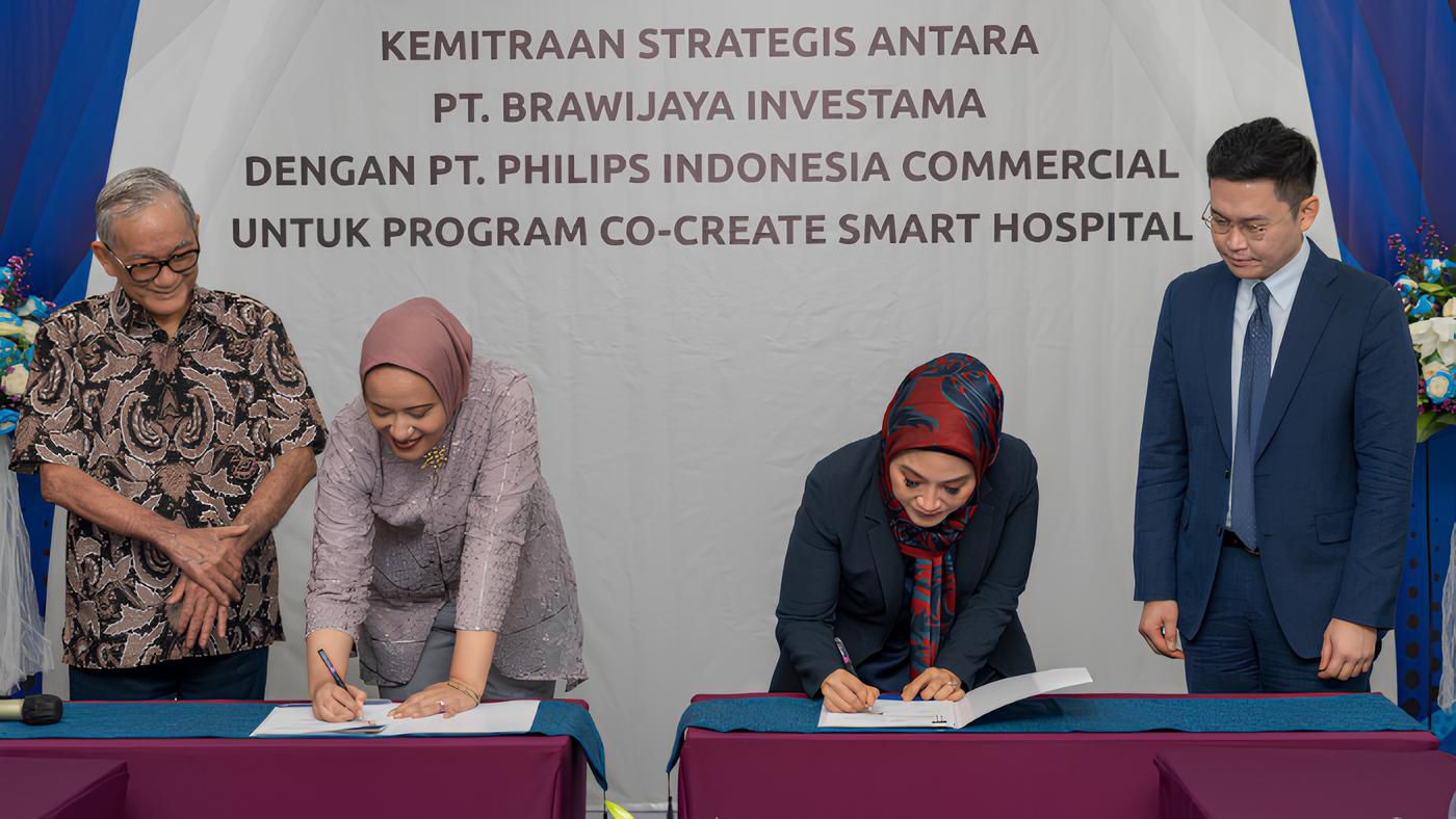 Astri Ramayanti Dharmawan dan Amira Ganis berjabat tangan sambil memegang MoU yang telah ditandatangani