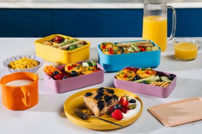 Bunte Lunchboxen gefüllt mit vorbereiteten Mahlzeiten und Obst
