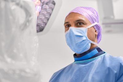 Zorgprofessional in beschermende kleding en mondmasker tijdens een medische procedure