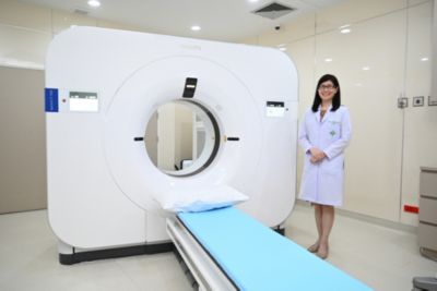 ภมดา สุวรรณพานิช ยืนเคียงข้างเครื่องเอกซเรย์คอมพิวเตอร์สเปกตรัม Philips Spectral CT ในห้องรังสีวิทยาของโรงพยาบาล