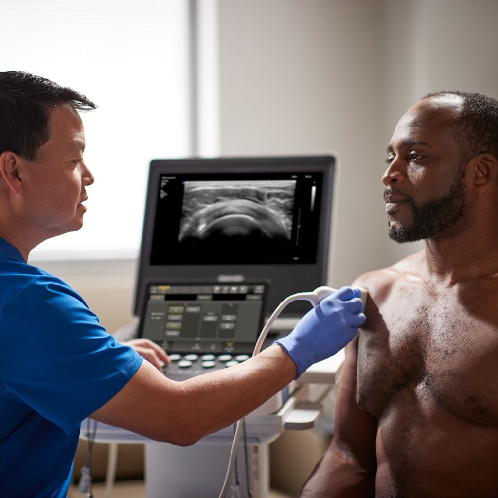 MSK Clinician consulting patient in front of mobile ultrasound system