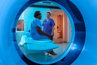 Clinician speaks with patient seated on table viewed through Philips CT scanner bore
