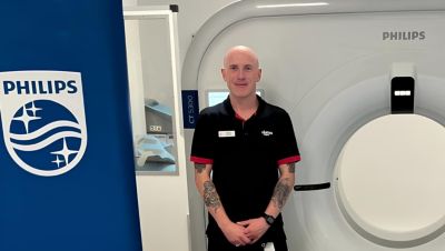 Lumus Imaging employee standing in front of ct scanner in imaging suite