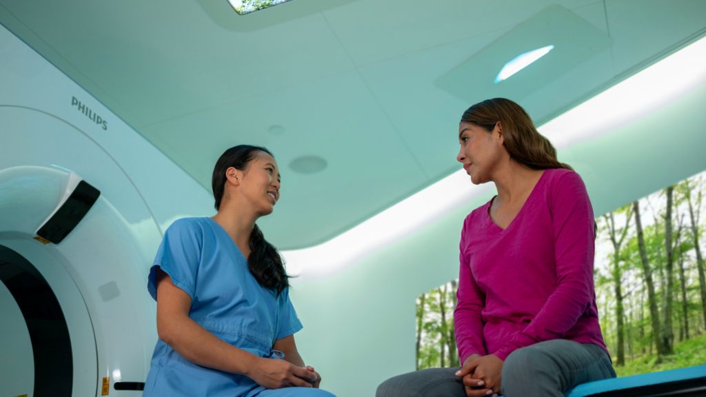 Radiographer comforting patient in a CT exam room with CT 7500 with Ambient Experience.