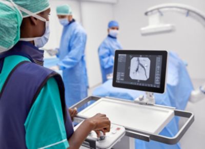 Profissional de saúde operando o arco cirúrgico móvel Zenition durante um procedimento vascular