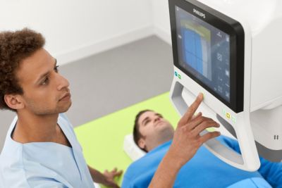 Clinician adjusts Philips imaging system on touchscreen while patient lies on examination table