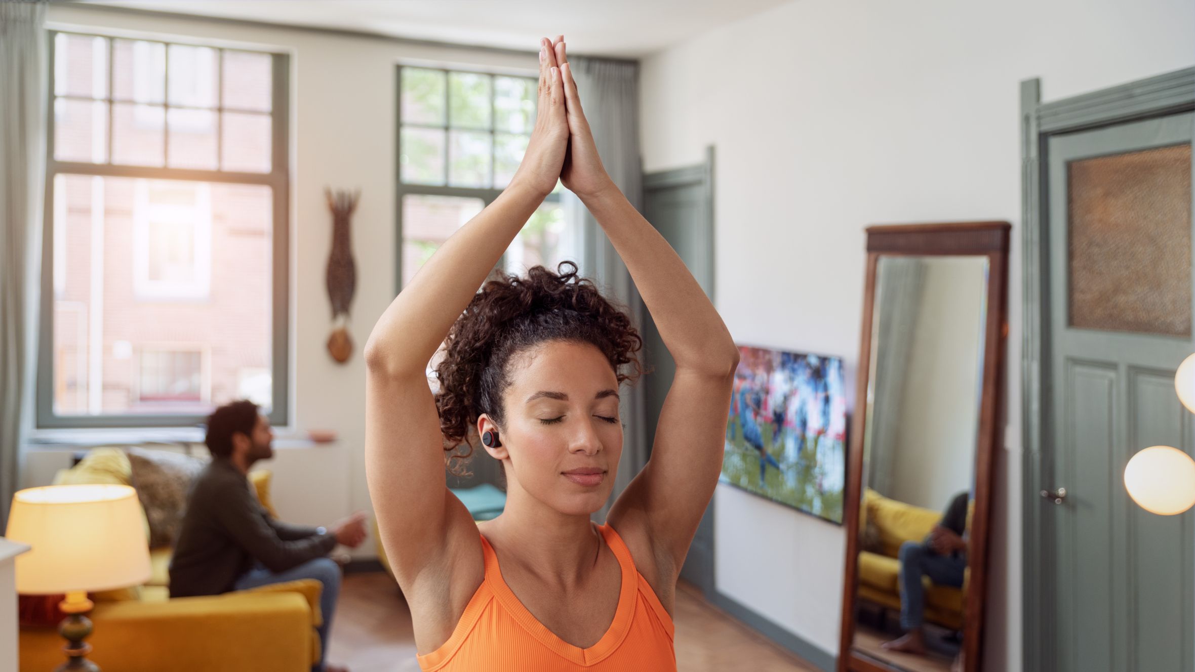 Woman doing yoga indoors with Philips noise-canceling headphones on