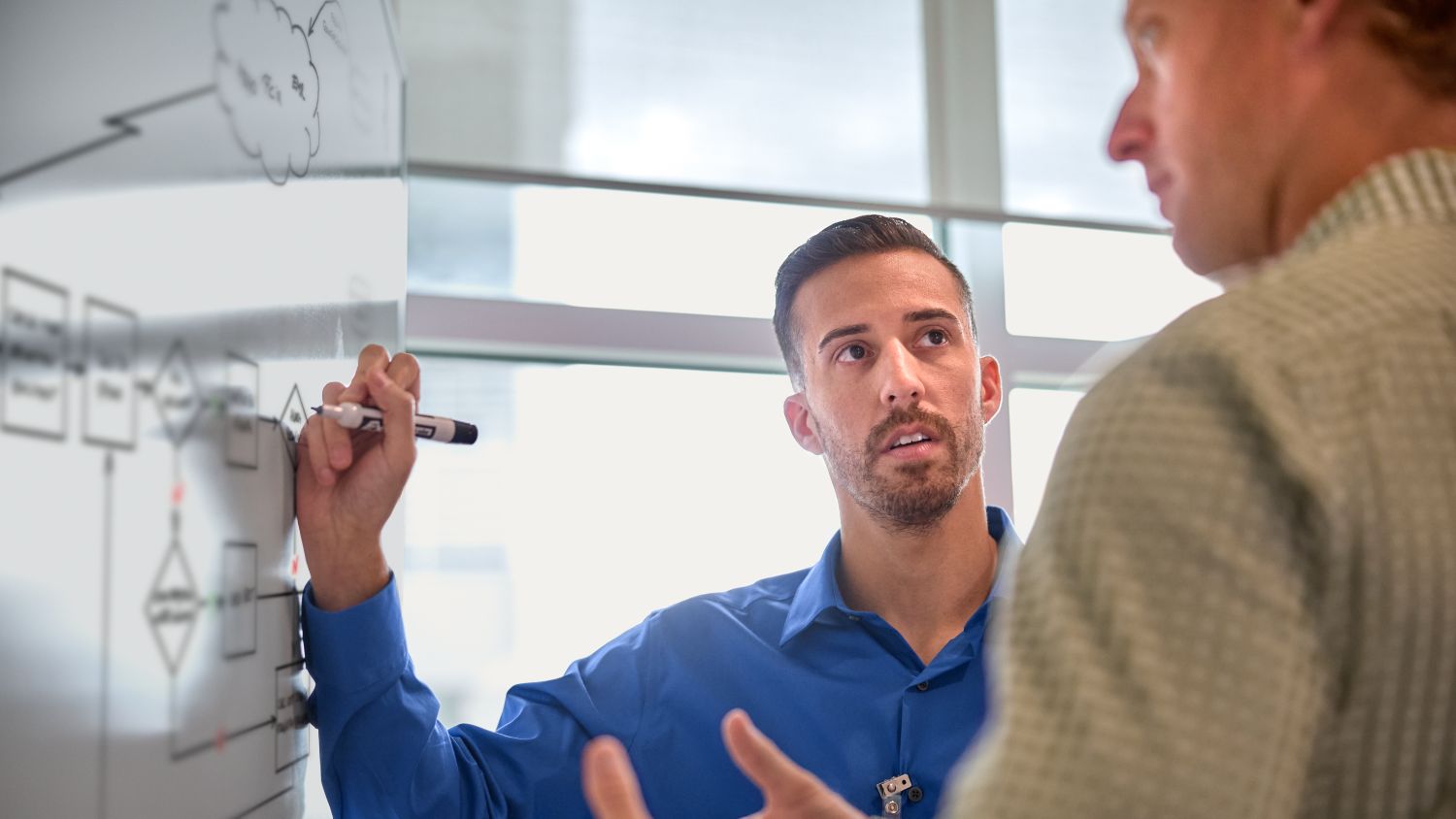 two men in classroom writing on a whiteboard