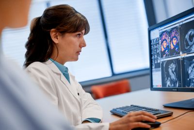 Female radiologist analyzing color-coded brain MRI reconstructions at her diagnostic workstation