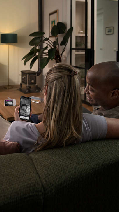 A couple watching their baby via their phone and the baby monitor