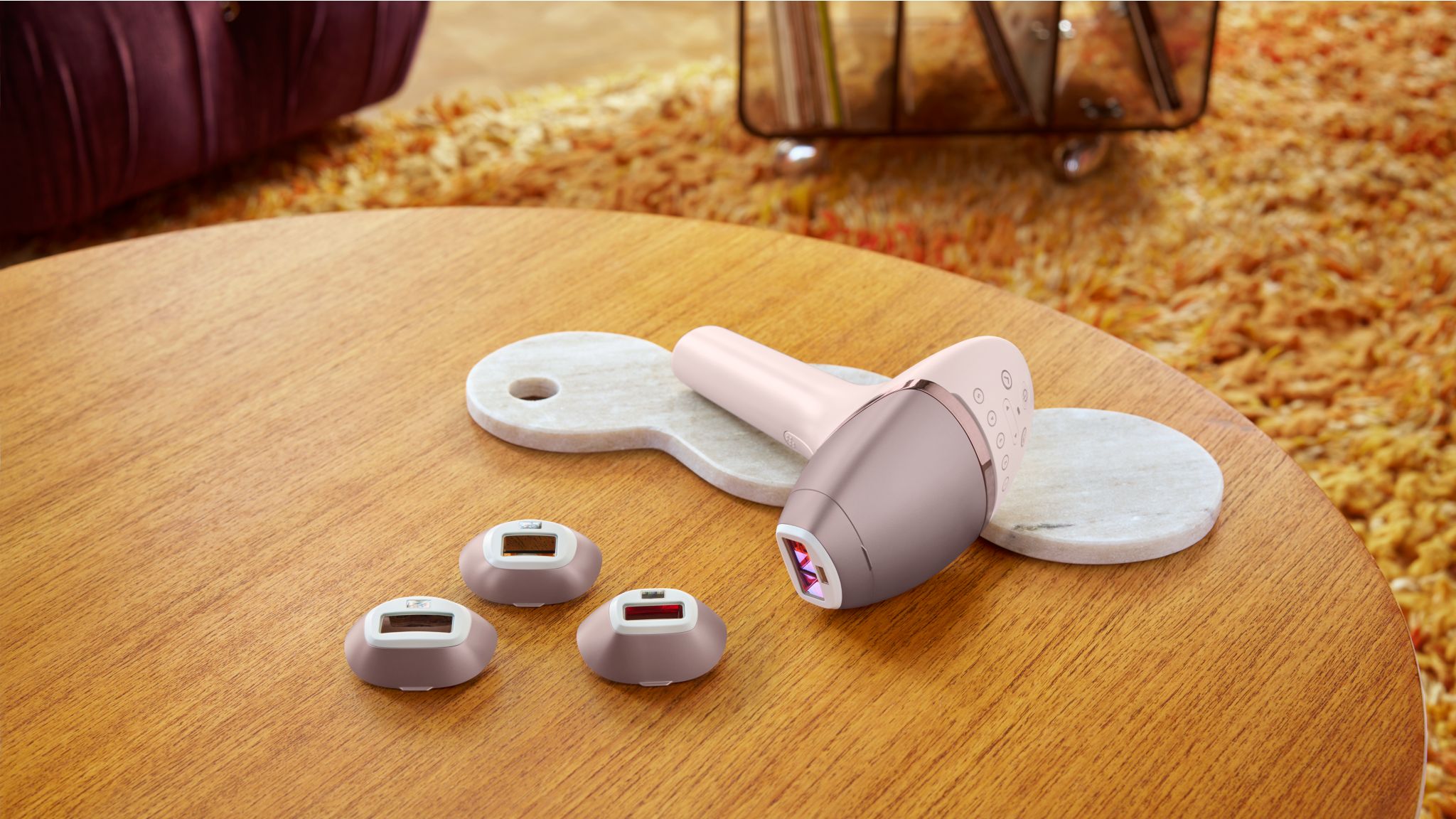 A product image of a Philips Lumea IPL device and attachments on a woodan table.
