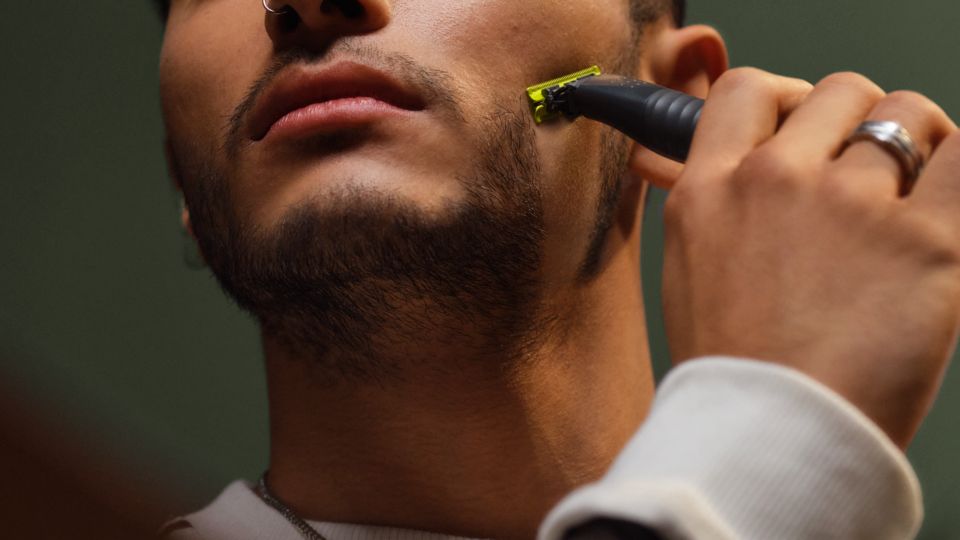 En närbild av en ung man som rakar sitt skägg med en Philips OneBlade.