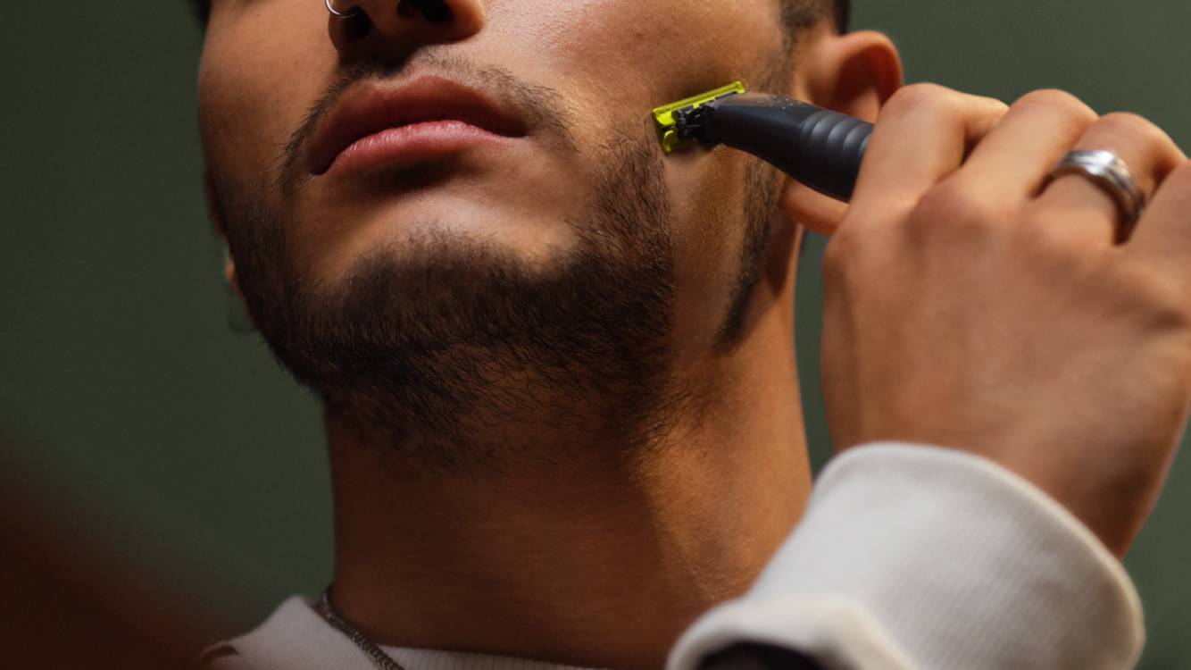 Eine Nahaufnahme eines jungen Mannes, der seinen Bart mit einem Philips OneBlade rasiert.