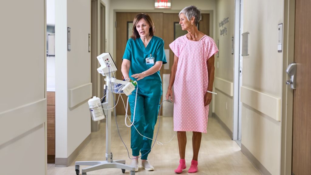 Patient walking with nurse while looking at Patient Monitor 6300 in hallway