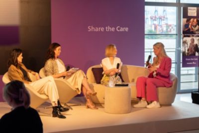 Podiumsdiskussion mit Referenten auf der Bühne unter Share the Care Message