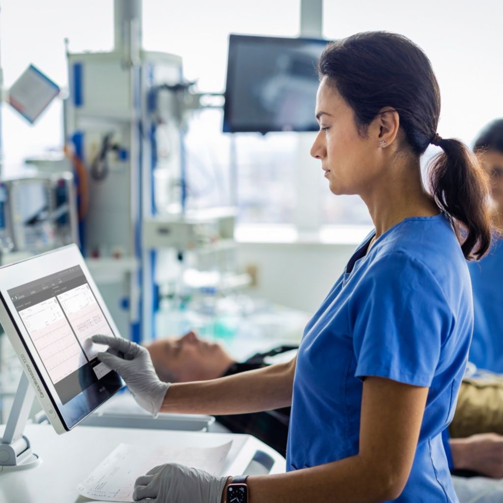 A healthcare professional uses the touchscreen on the Cardiac Workstation to review patient data at the bedside.