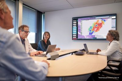 Zorgprofessionals in een vergaderruimte bekijken kleurrijke digitale medische beelden op een groot wanddisplay