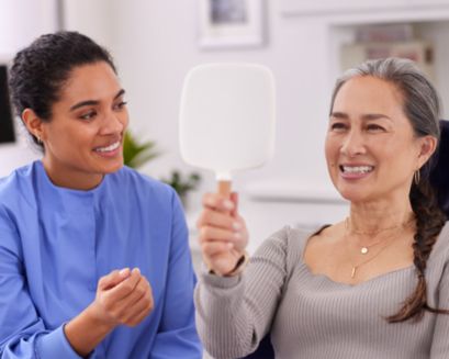 A patient in a dental chair admiring her smile in a mirror.