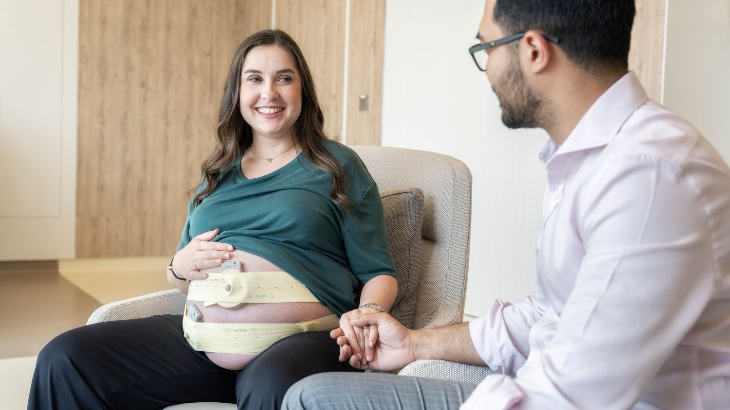OB patient sitting in a chair holding hands with partner