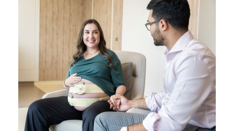 OB patient sitting in a chair holding hands with partner