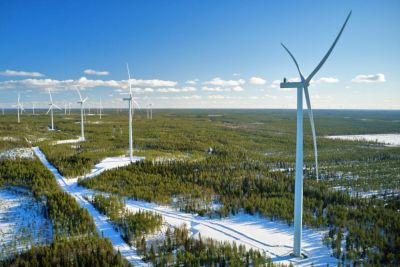 Wind turbines operating in snow-covered forest landscape