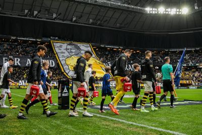 AIK- och Siriusspelare går in på planen med Philips hjärtstartare (AED)