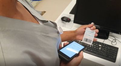 Profissional de saúde escaneando a pulseira do paciente com um dispositivo móvel usando o sistema Tasy