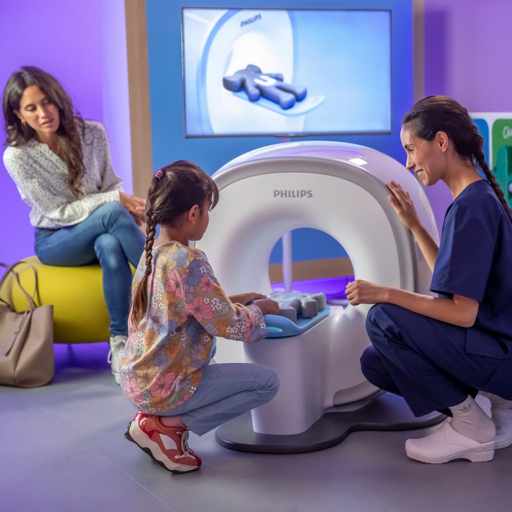 Pediatric Coaching solution - Mother, nurse and girl with Kitten Scanner sliding in Ollie the elephant prior to the MRI exam.