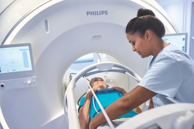 Radiology technologist preparing patient for MRI scan using Philips system