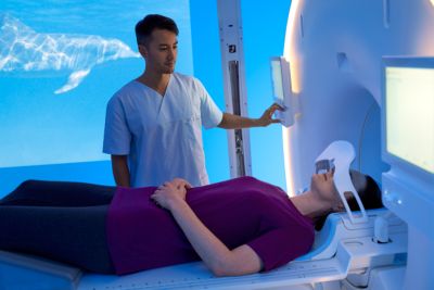 Close-up of radiology professional operating Philips MR system while patient lies in scanner
