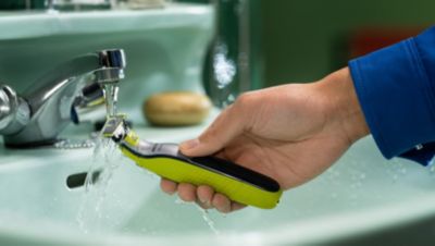 Elektrischer Trimmer, der unter fließendem Wasser an einem Waschbecken abgespült wird