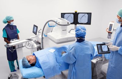 Zorgprofessionals gebruiken een Philips Azurion-systeem voor beeldgestuurde therapie met mobiele C-boog en twee monitoren tijdens een minimaal invasieve procedure bij een patiënt