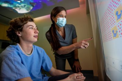 Pediatric patient interacting with Ambient Experience touchscreen with healthcare professional