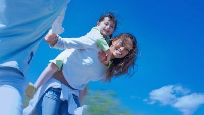 Elternteil trägt ein junges Kind bei einem gemeinsamen Familienausflug im Freien