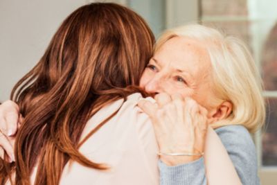 Elderly woman hugging a younger adult woman