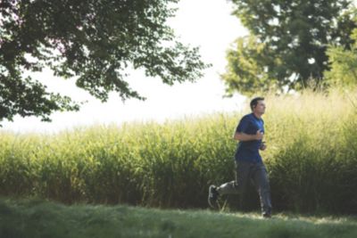 Man running outdoors in grassy field representing active lifestyle with sleep apnea therapy