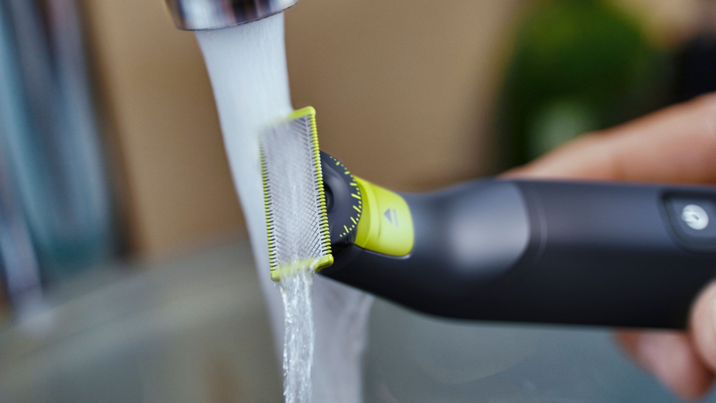 A close up picture of a Philips OneBlade being washed under a faucet. 